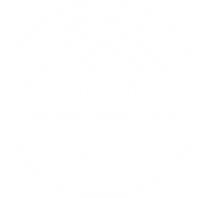 Knowles Construction logo with a blue and white color scheme. The logo features the text "Knowles Construction" in bold blue letters beneath an image of three rooflines, symbolizing houses, with the establishment year "Est. 2017" above. The design is encircled with a semi-circular border and a wave pattern below the text.